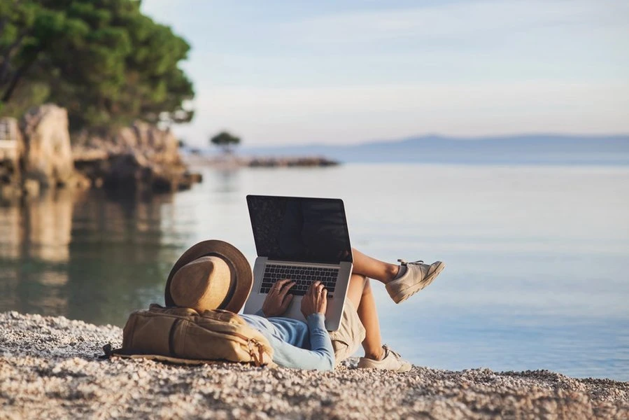 A person working on a laptop in a cafe setting, illustrating the digital nomad lifestyle.